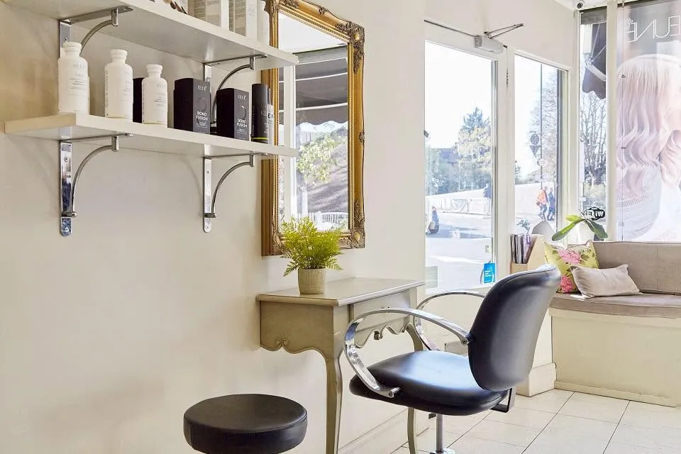 Modern styling chair and elegant gold mirror inside Emilia Hair Studio