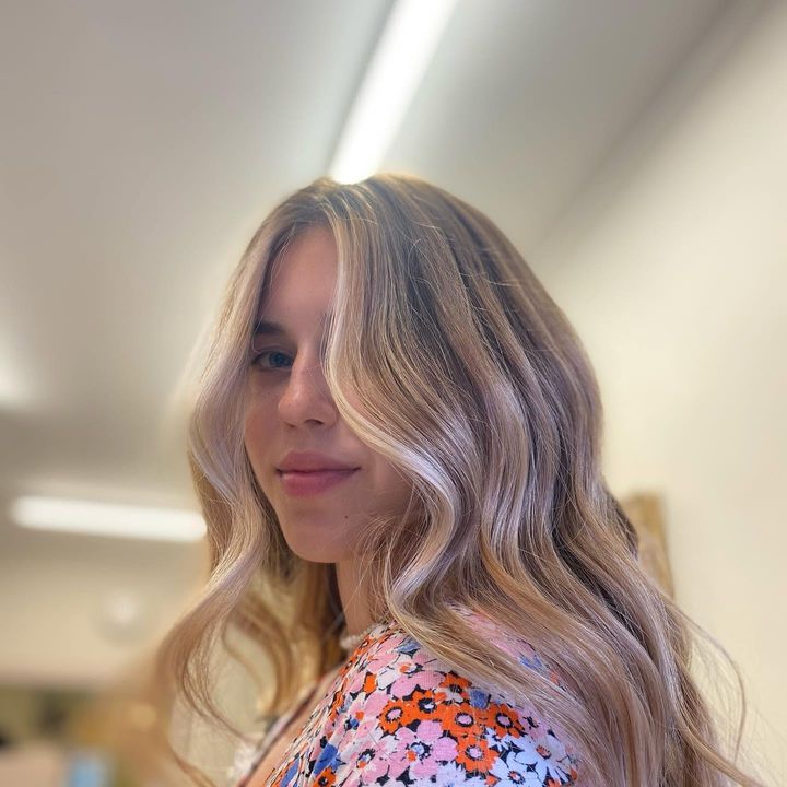 Client with long, wavy hair in blended blonde tones with face-framing highlights