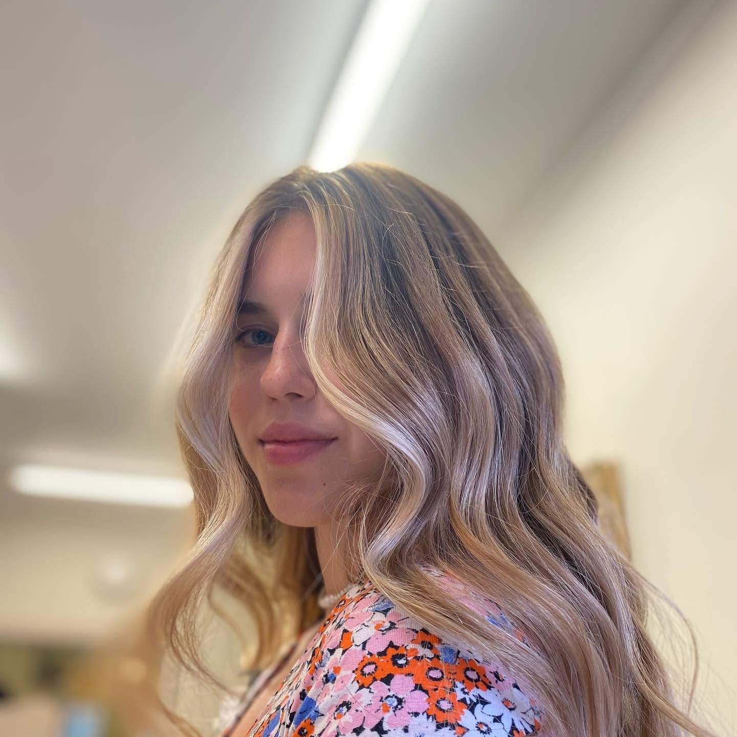 Client with long, wavy hair in blended blonde tones with face-framing highlights