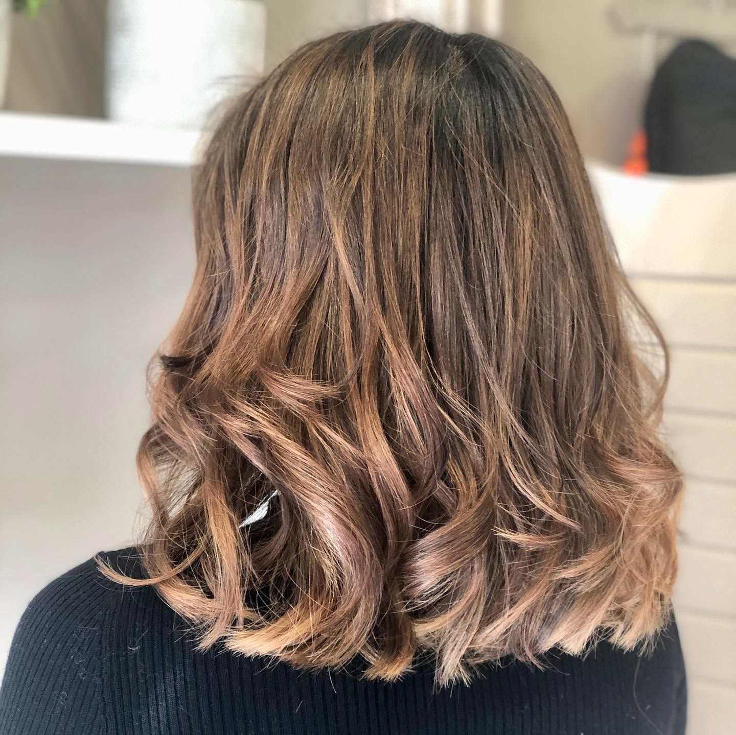 Back view of shoulder-length brown hair with caramel balayage in loose waves