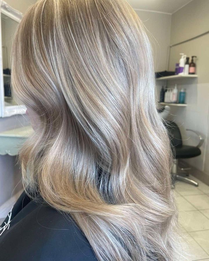 Side view of long, layered blonde hair with champagne tones in loose waves
